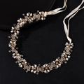 Elegant gold bridal headband with sparkling rhinestones and white pearls on black background - Gold