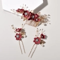 Close-up of bridal hair pins set with burgundy fabric flowers and golden metal leaves - Burgundy