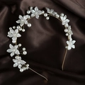 Detail of floral headband featuring pearl accents and gold frame on satin background - Gold