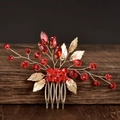 Close-up of red crystal beads and golden metal leaves on a handmade bridal hair comb - Red
