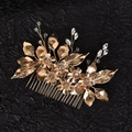 Nahaufnahme von goldenem Braut-Haarkamm mit Metallblumen und Kristallen auf schwarzer Seide - Gold