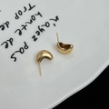 Boucles d'oreilles élégantes dorées en forme de C sur une assiette en céramique blanche - Doré