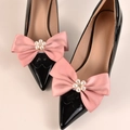 Dettaglio di décolleté in vernice nera con fiocchi di raso rosa e ornamenti di fiori di perle - Stile Perla Rosa