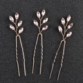 Dettaglio di tre forcine per capelli dorate con pietre di cristallo rosa su nero - Rosa