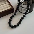 Minimalistische Halskette aus schwarzem Onyx und weißem Türkis auf Holzschatulle - Schwarz