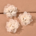 Dettaglio ravvicinato di tre fermagli per capelli a fiore crema con perle su tessuto - Beige