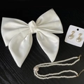Set sposa con fiocco in raso bianco, collana di perle e orecchini su sfondo di legno nero - Set di Fiocco per Capelli Collana Orecchini