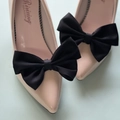 Dettaglio di eleganti fiocchi in raso nero su décolleté a punta color carne da sposa - Nero