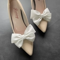Dettaglio di eleganti fiocchi in tessuto bianco su scarpe da sposa in vernice beige a punta - Bianco puro