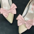 Detailed macro view of cream patent leather pointed toe shoes with silk pink bow decoration - Pink
