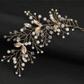 Diadema de novia dorada con hojas, perlas y cristales sobre soporte negro elegante - Dorado