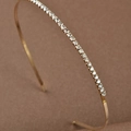 Macro di cerchietto placcato oro con strass trasparenti su sfondo scuro con texture - 1 Fila Oro