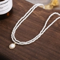 Elegante zweilagige Perlenkette mit ovalem Anhänger im Goldrahmen auf Holzgrund - Ovaler Anhänger Stil (Stil 1)