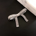 Elegant silver bow hair clip with sparkling rhinestones on marble and leather background - Silver