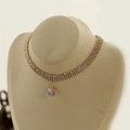 Elegante vierreihige Strass-Halskette mit großem Kristallanhänger auf einem Display - Strassanhänger Stil - Gold