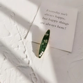 Dettaglio di un fermaglio ovale verde scuro con motivi floreali e tre piccole perle - Verde scuro con fiore bianco