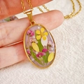 Handmade gold oval resin pendant with dried flowers and pearls held in hand - Oval Yellow Dried Flower with Artificial Pearl - Style E