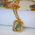 Primer plano del colgante dorado rectangular con flores blancas reales y hoja en resina - Estilo de Hoja