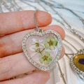 Close-up of heart resin pendant with dried flowers and white rhinestones on silver chain - White & Green Dried Flowers, Light Pink Base (Style F)