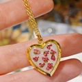 Close-up of handmade heart pendant with real pink dried flowers and gold steel frame - Sweet Alyssum Heart Locket Necklace