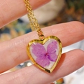 Macro detail of handmade heart necklace with purple dried flower and golden frame - Hydrangea Heart Locket Necklace