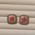 Macro shot of square vintage earrings with orange dried flowers and gold hollow frames - Orange Flower Style