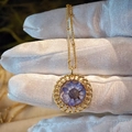 Macro shot of circular gold hollow pendant with purple dried flower and bead chain - Purple