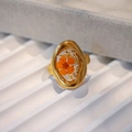 Macro detail of handmade stainless steel ring with dried flowers in oval resin inlay - Orange