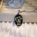 Detailed close-up of handmade oval dried flower pendant on a beige jewelry display - Oval Style B