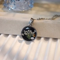 Macro shot of circular resin pendant with white dried flowers on stainless steel chain - Round Type B