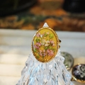 Macro detail of oval floral resin ring with pink dried flowers and golden wavy border - Gold