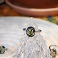 Macro shot of silver ring with white dried flower embedded in black resin on crystal stand - Snow