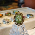 Macro detail of a vintage bronze lace ring with green resin and white dried flowers - J Style Antique Bronze