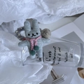 Detail showing hand-knitted grey rabbit hair tie with a pink scarf and fuzzy tassels - Gray