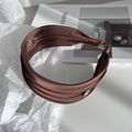 Close-up of brown satin wide headband featuring a polished silver metal logo disc - Brown