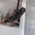 Detailopname van glanzende zwarte en zilveren steentjes op een geplooide bananenklem haardecor - Gunmetal