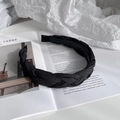 Detail view of a black twisted fabric headband with pleated texture on an open magazine - Black