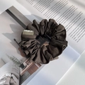 Vue détaillée d'un chouchou en tissu plissé marron foncé sur un magazine ouvert - Vert & Café