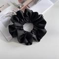 Detailed close-up of a classic black satin scrunchie with elegant folds on a white surface - Black