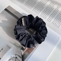 Detail of a black fabric scrunchie with a brown woven label on a magazine background - Navy Blue