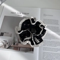Detail van bloemenstof scrunchie met witte geschulpte randen en handgemaakt textiellabel - Bloemig Contrast Stijl / Zwart