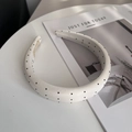 Close-up of padded white headband with black polka dots and fine fabric texture - Beige