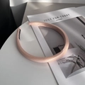 Detalle de diadema acolchada de satén rosa sobre mesa blanca con una revista - Naranja