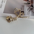 Dettaglio di un mollettone per capelli dorato con design realistico a rosa e cuore - Oro Grande