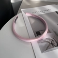 Detalle de diadema de satén rosa acolchada con etiqueta artesanal sobre mesa blanca - Rosa