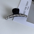 Dettaglio di una pinza per capelli nera curva con due file di strass bianchi brillanti - Grande (11,5 cm)