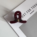 Detail of burgundy hair claw clip featuring a black bow and gold metal centerpiece - Red
