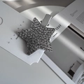 Nahaufnahme der funkelnden Strass-Stern-Haarspange auf weißer Karte mit Metalldetail - Pentagramme