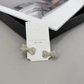 Dettaglio macro di fermagli per capelli a fiocco dorato con cristalli bianchi su carta - Stile Strass Dorato