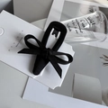 Detail of elegant black fabric bow hair clip on a minimalist brand display card - Black